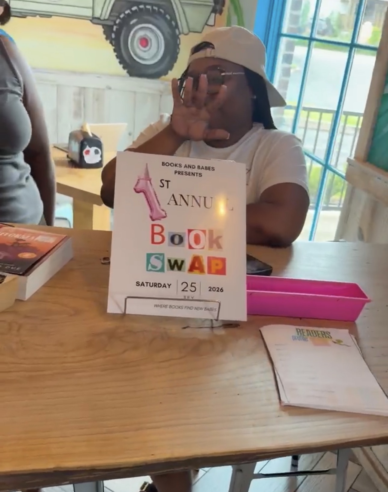 A guest beside the first annual Books and Babes book swap sign